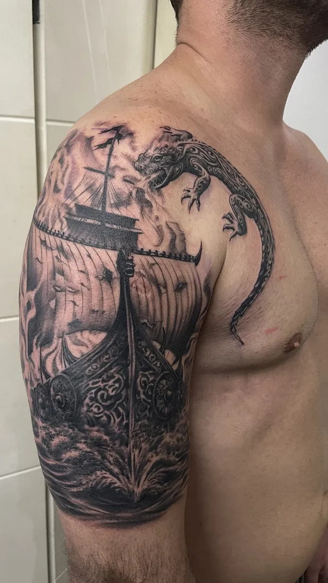 Tatuagem de navio viking em realismo preto e cinza no braço